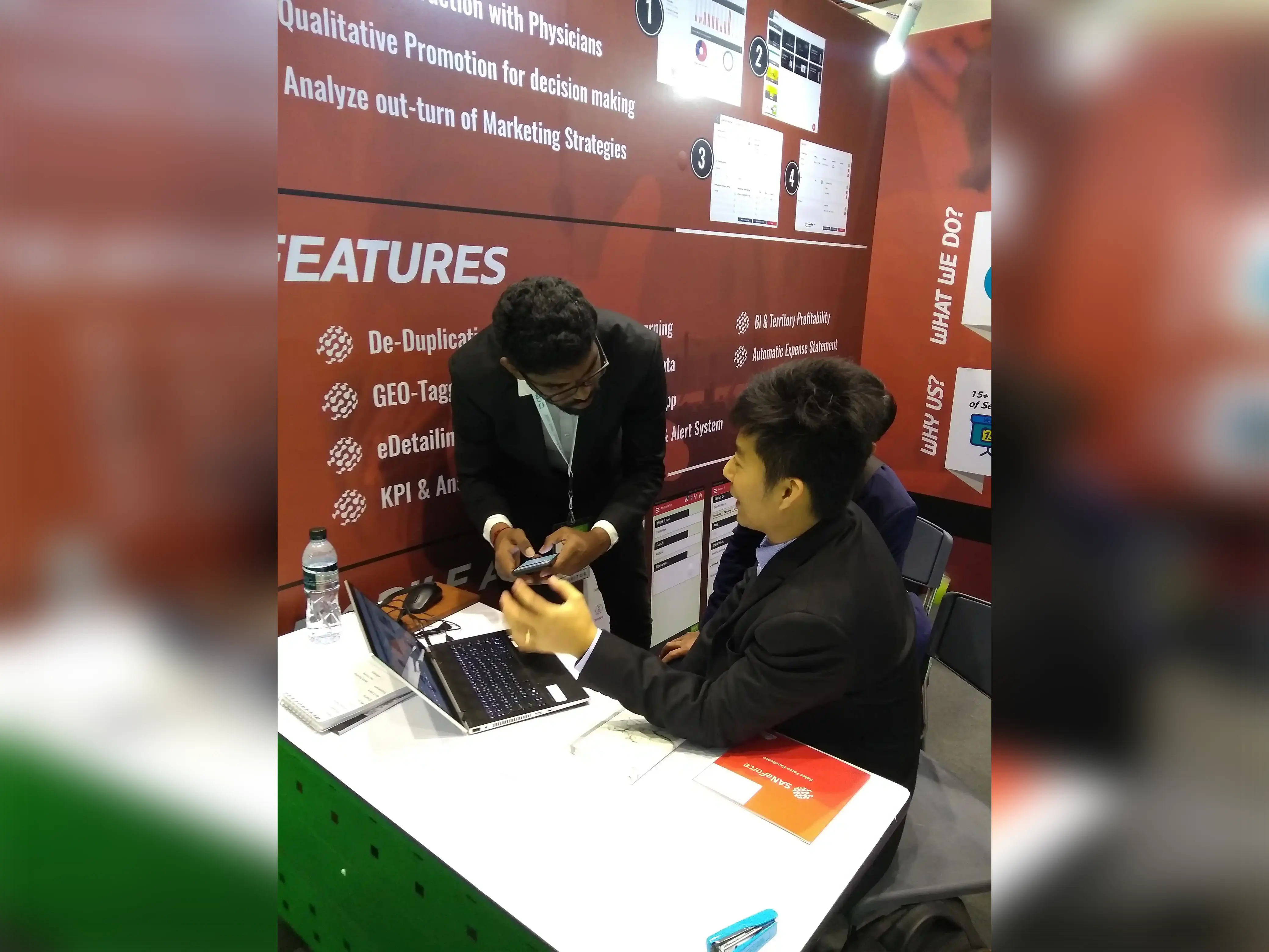 Two suited men engage with a laptop, highlighting SANeForce Solutions during CPHI in Bangkok, Thailand, March 12-14, 2019.